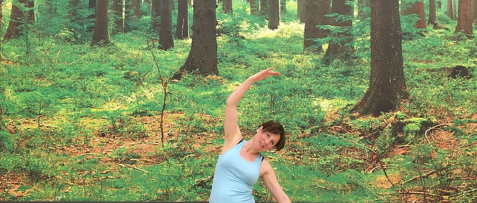 Julia demonstrating a Pilates stretch outdoors